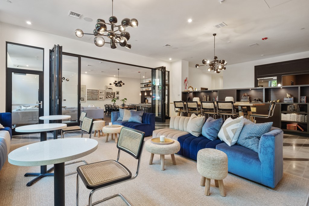 a living room with blue couches and tables and a dining room