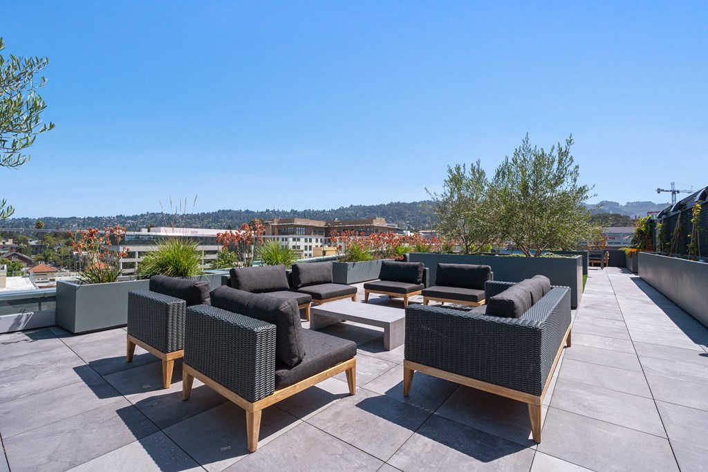 a roof top patio with furniture and a city in the background