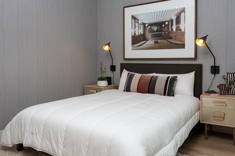 A bedroom with a white bed and a picture on the wall.