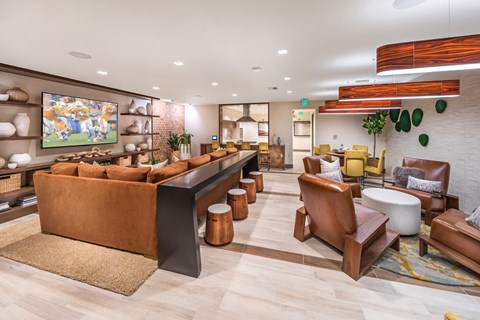 A living room with a brown sofa and wooden chairs.