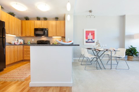 A kitchen with wooden cabinets and a white island with a dining table and chairs.