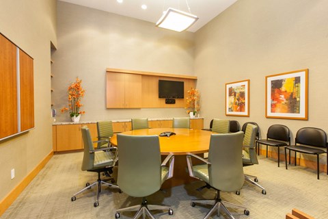 Conference room with wooden table and orange accents at The Grand Apartments, California, 94612