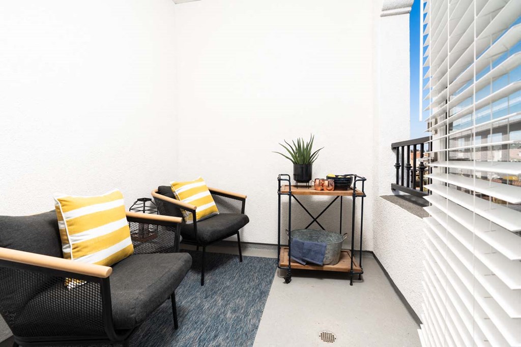 a balcony with chairs and a table and a window