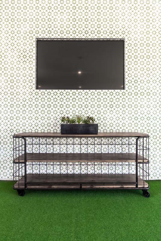 a television is hanging on the wall above a shelf with plants