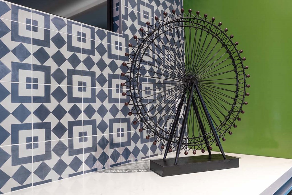 a statue of a ferris wheel in front of geometric tiles