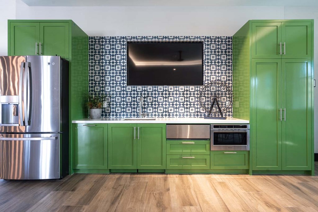 a kitchen with green cabinets and a stainless steel refrigerator