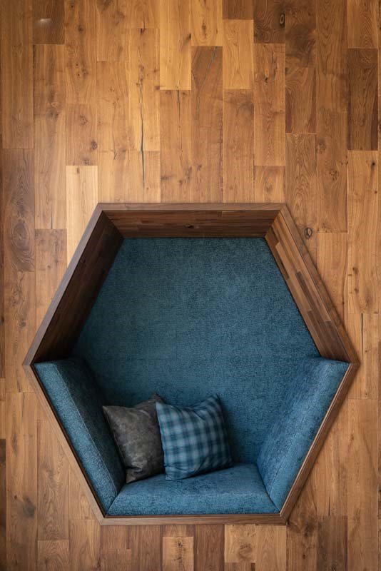 a blue couch in a window with wood floors