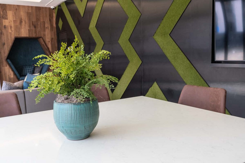 a white table with a blue vase with a plant on it