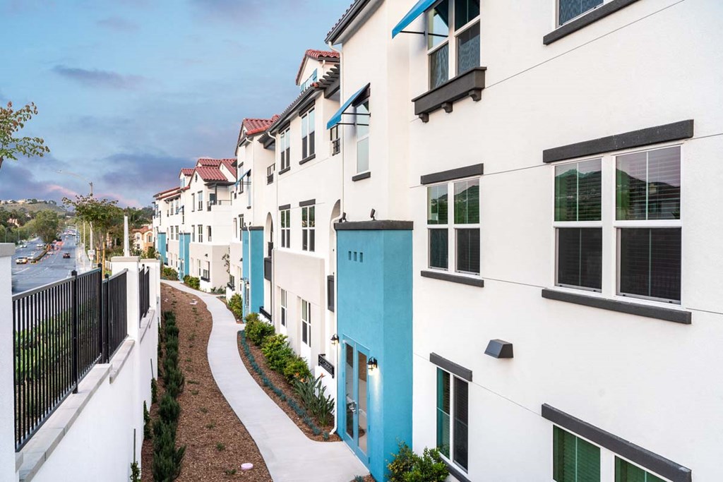 a row of white houses with blue doors on a sidewalk