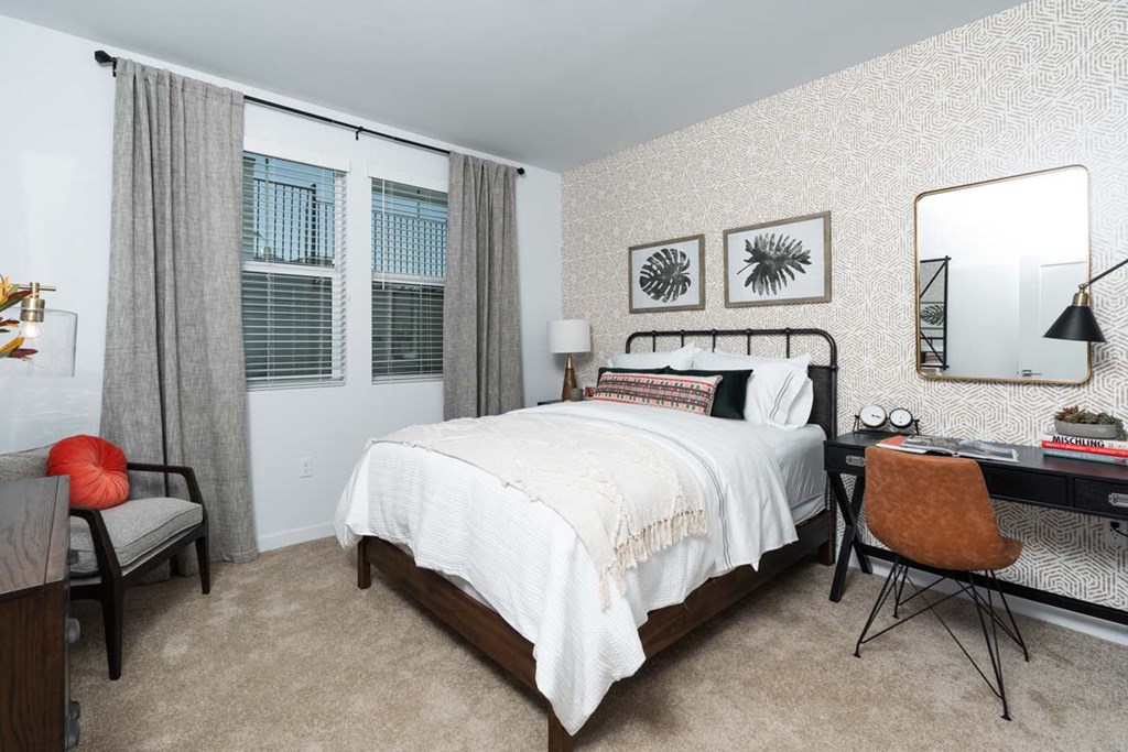 Dog-Friendly Apartments in Corona, CA - The Monterey Corona - Bedroom with Plush Carpeting, a Desk, and a Queen Size Bed with a Nightstand