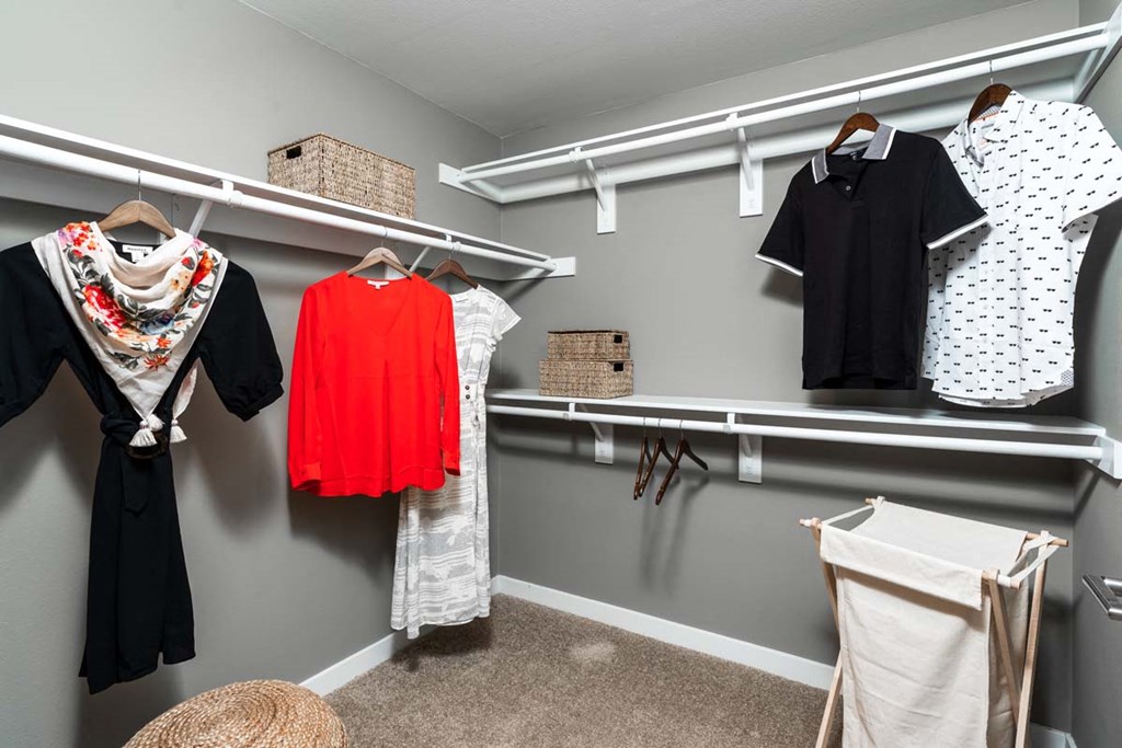 a walk in closet with a rack of clothes and a dresser