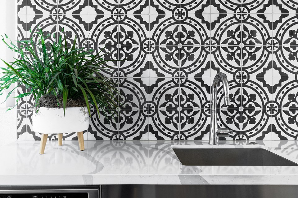 a kitchen with black and white wallpaper and a plant