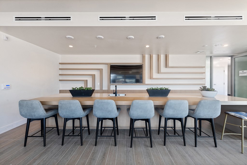 a long bar with blue chairs in a room with a sink