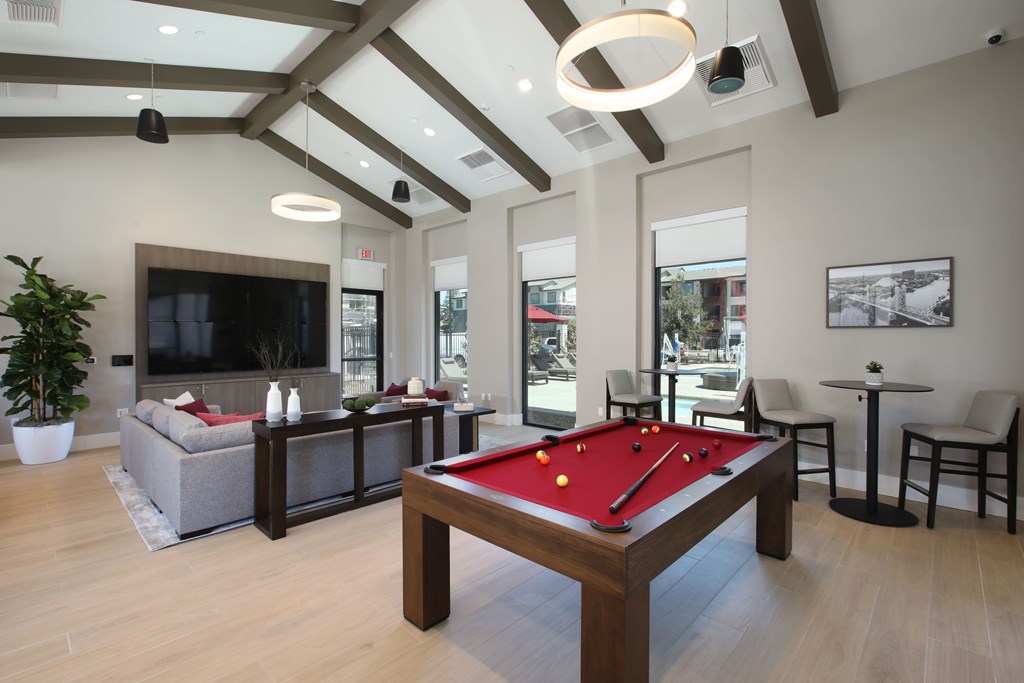 A pool table is in the middle of a room with a couch, chairs, and a television.