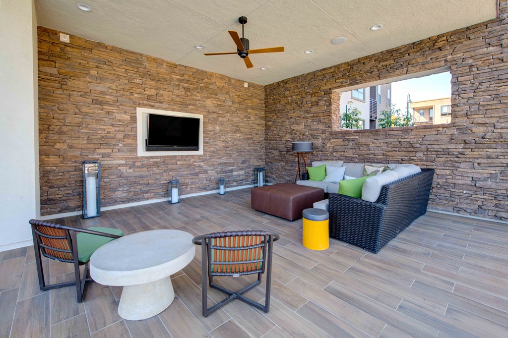 a patio with a couch table and chairs and a flat screen tv