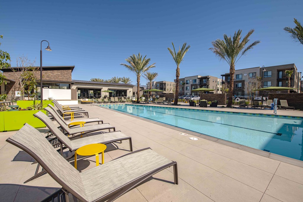 Apartments Redlands, CA - The Summit - Pool With Lounge Chairs, Yellow Side Tables, Tables With Chairs Around and Green Umbrellas