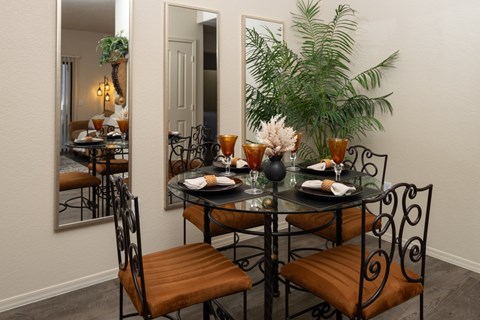 A dining table with chairs and a mirror reflecting a dining room.