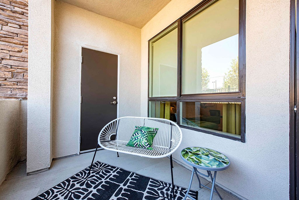 a chair and table sit on a balcony in front of a door