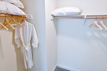 a walk in closet with robes and pillows and a shelf with a white robe