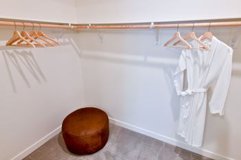 a closet with white robes and a wooden stool
