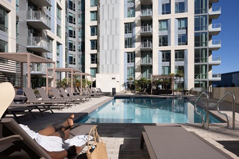 A person is sunbathing by a pool in front of The Martin