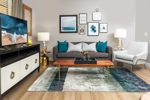 A living room with a grey couch, a wooden coffee table, and a painting on the wall.