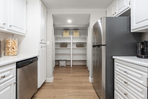 A kitchen with white cabinets and a stainless steel refrigerator.