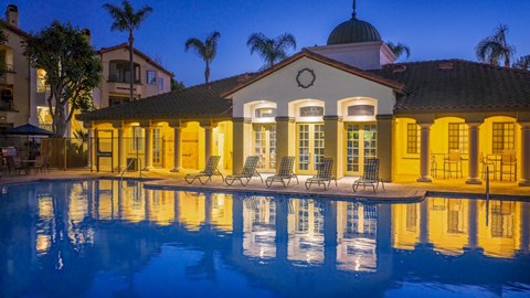 Evening pool with lounge chairs and clubhouse at Toscana at Rancho Del Rey Apartments, California