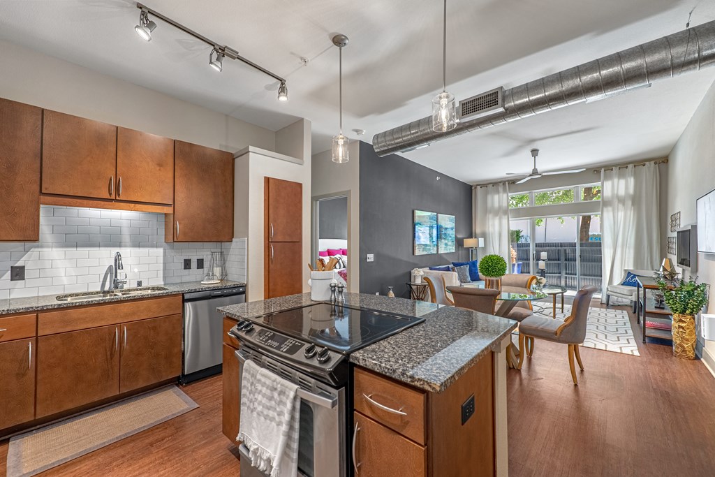 a kitchen with an island and a living room with a table and chairs at Trend Design District, Dallas, TX 75207
