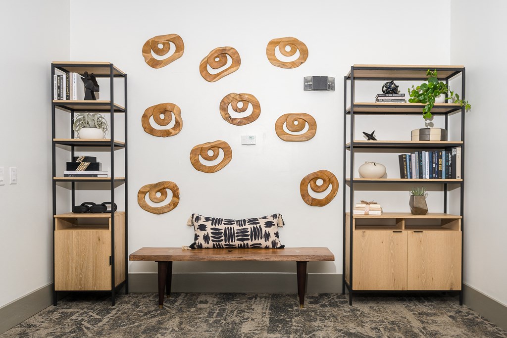 a room with two bookshelves and a bench with a pillow and a plant on it at Trend Design District, Dallas, Texas