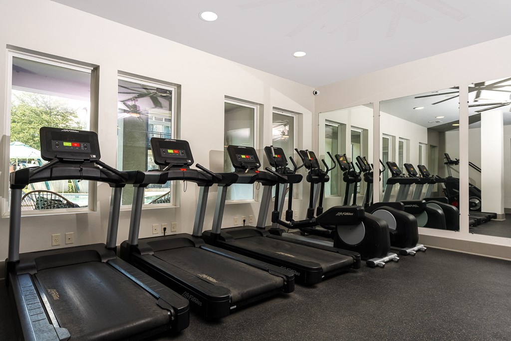 a row of treadmills and elliptical trainers in a gym at Trend Design District, Dallas, 75207