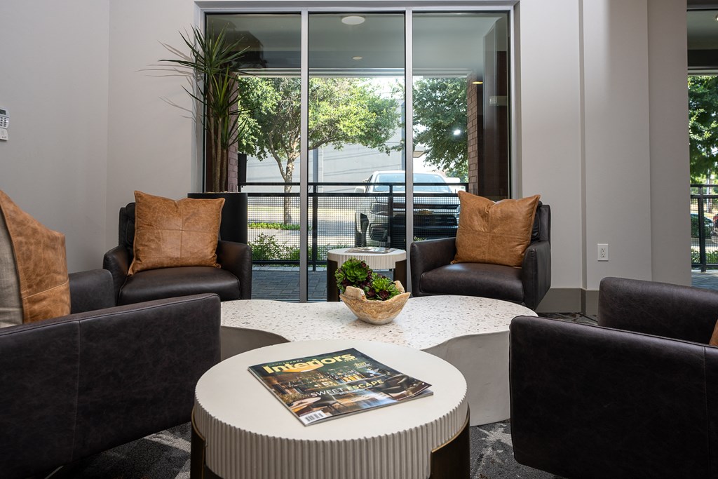 a living room with black leather chairs and a white coffee table with a magazine on it at Trend Design District, Texas 75207