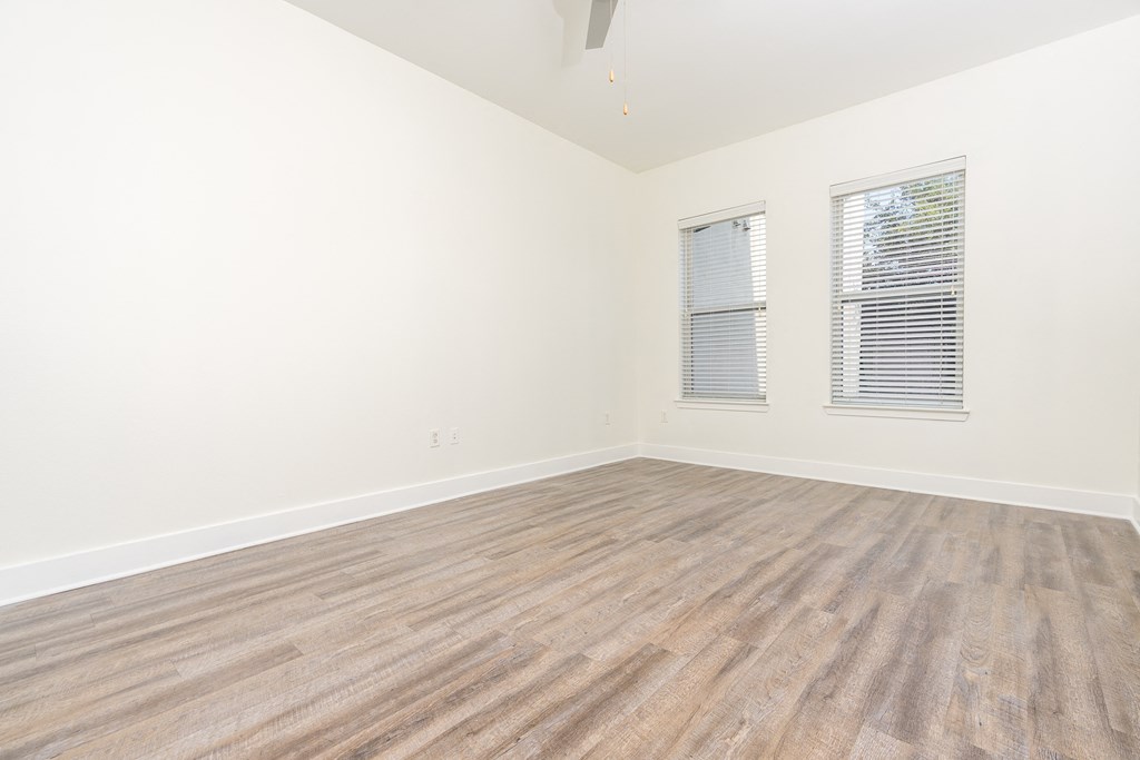 a bedroom with hardwood floors and white walls at Trend Design District, Dallas
