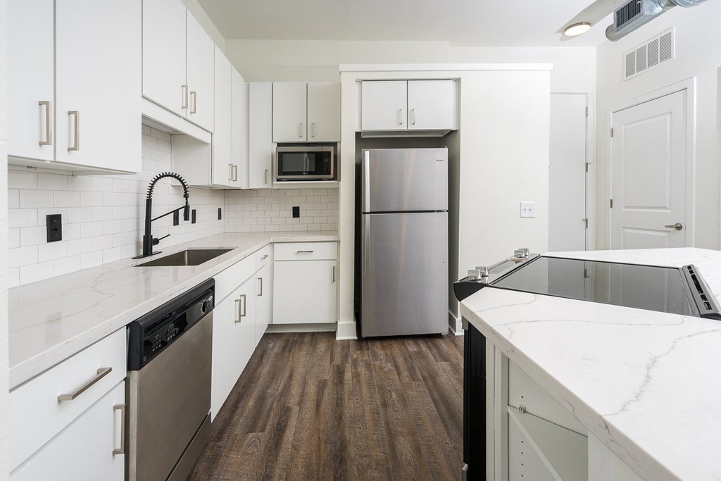 a kitchen with white cabinets and a stainless steel refrigerator at Trend Design District, Dallas