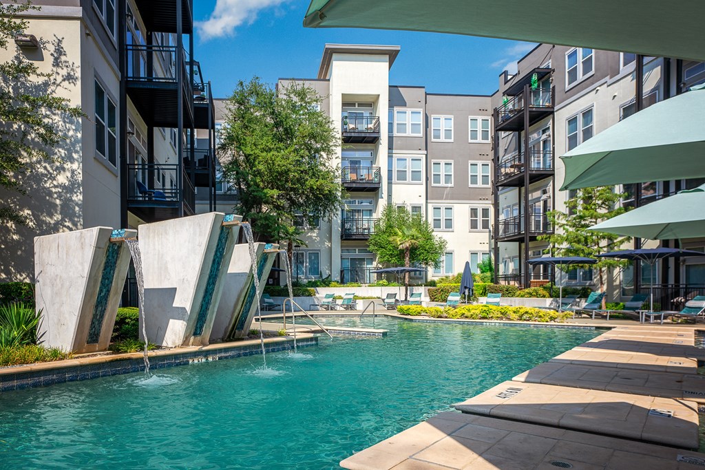 a swimming pool with water fountains and an apartment building in the background at Trend Design District, Texas 75207