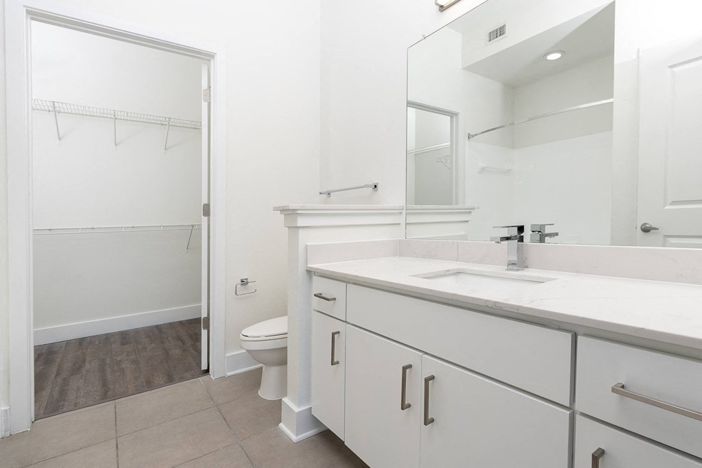 a bathroom with white walls and a large mirror at Trend Design District, Dallas, 75207