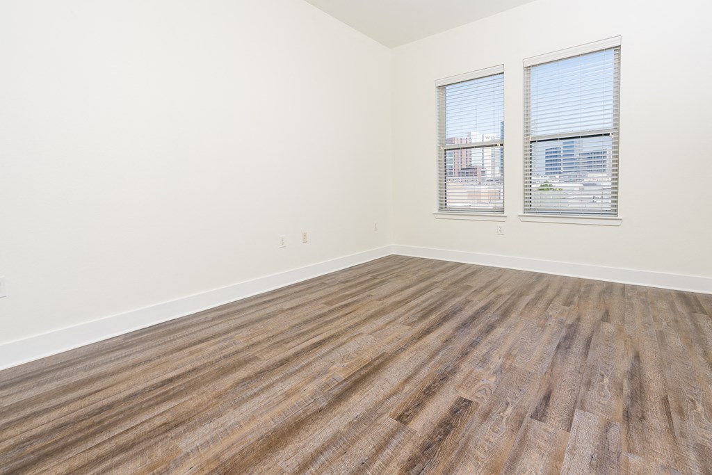 a bedroom with hardwood floors and white walls at Trend Design District, Texas 75207