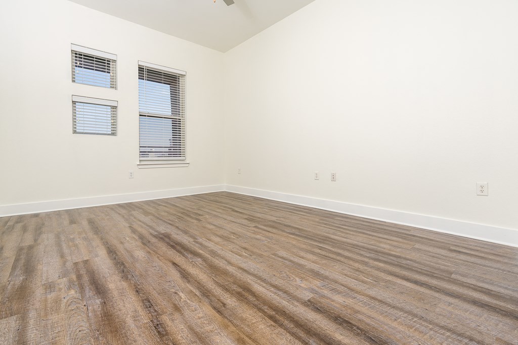 a bedroom with hardwood floors and white walls at Trend Design District, Dallas