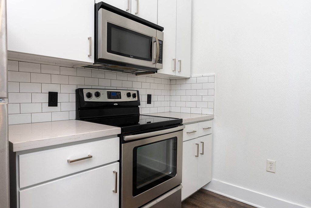 a kitchen with white cabinets and stainless steel appliances at Trend Design District, Dallas, TX