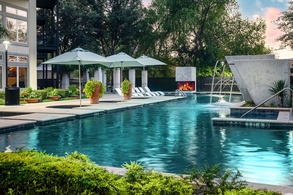 Resort-Style Swimming Pool with Lounge Chairs, Umbrellas, and Plants at Trend Design District, Dallas