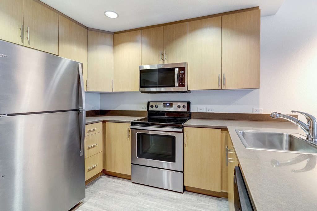 Kitchen with Stainless Steel Appliances, Wooden Cabinets, Quartz Countertops, and Hardwood-Style Flooring at Venue, California