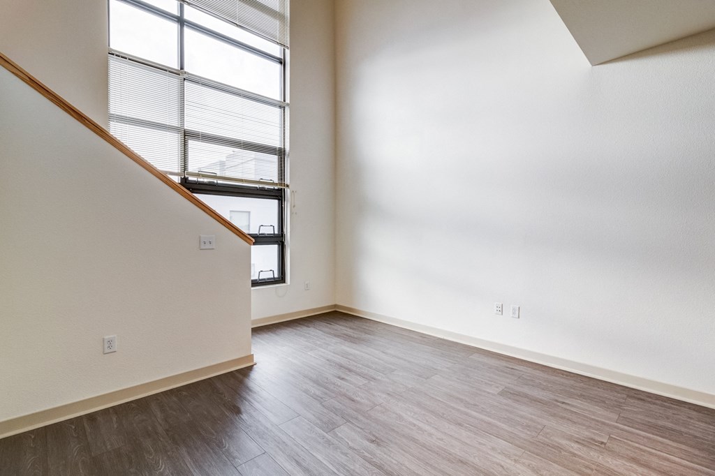 an empty living room with wood flooring and a large window in the loft space at Venue, San Francisco, California