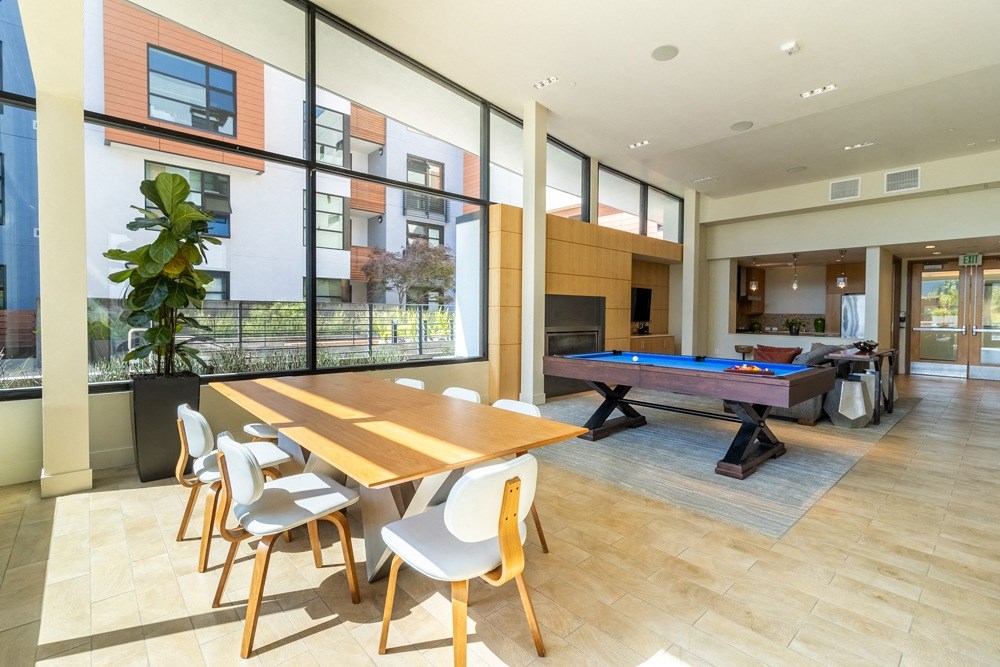 A room with a long table and chairs and a pool table.