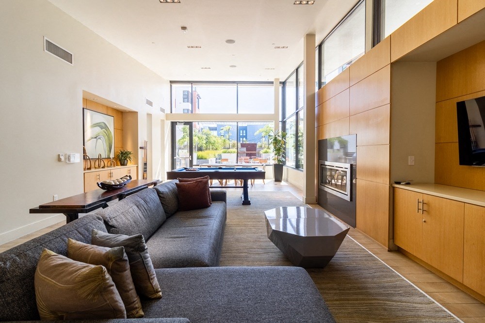 A modern living room with a grey couch and a large window.