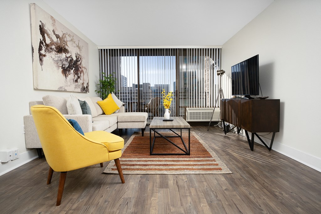 Livingtoom with yellow chair, flat screen TV , enterainment center, coffee table  and rug