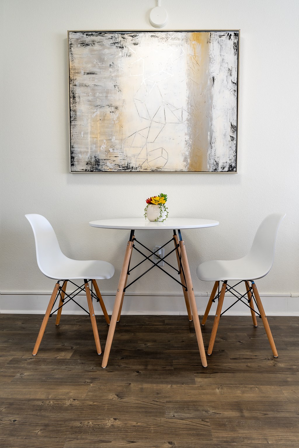 White Chairs and table with artwork on the wall