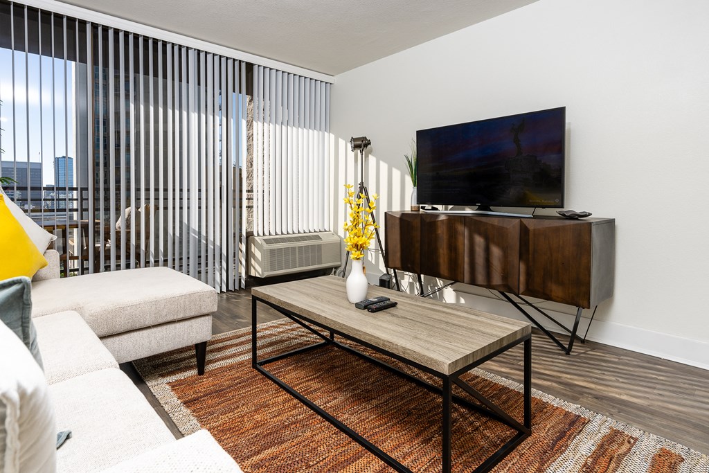 livingroom with seating, flat screen TV, entertainment center and large windows