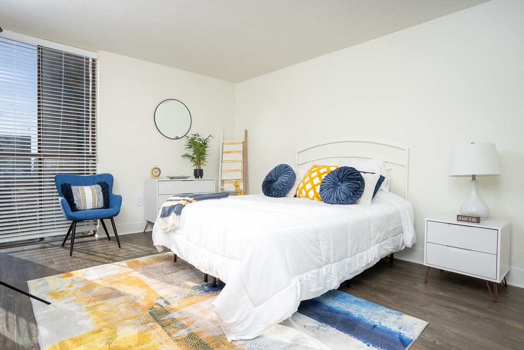 bedroom with white nightstand and light, large windows