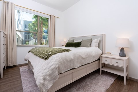 A bedroom with a large bed and a window with curtains.