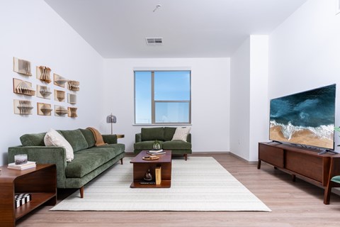A living room with a green couch, a coffee table, and a large painting on the wall.